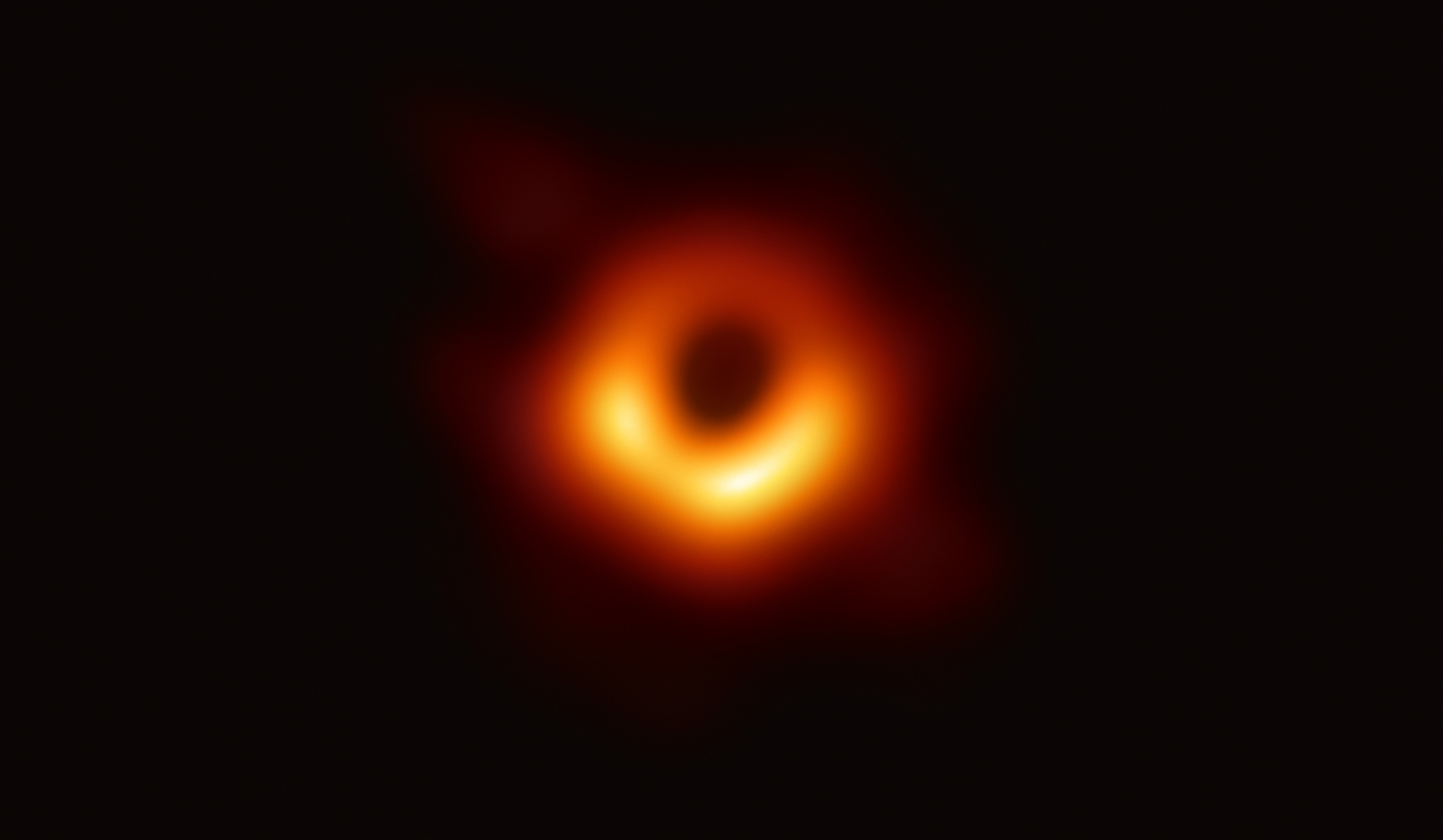 Première image de l'ombre du trou noir supermassif M87*, représentée par une région sombre entourée d'un anneau lumineux orange